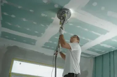 A professional worker sanding the ceiling during a home renovation project. Indoor construction setting.